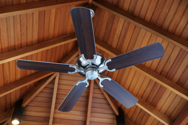 A ceiling fan on a wooden ceiling.